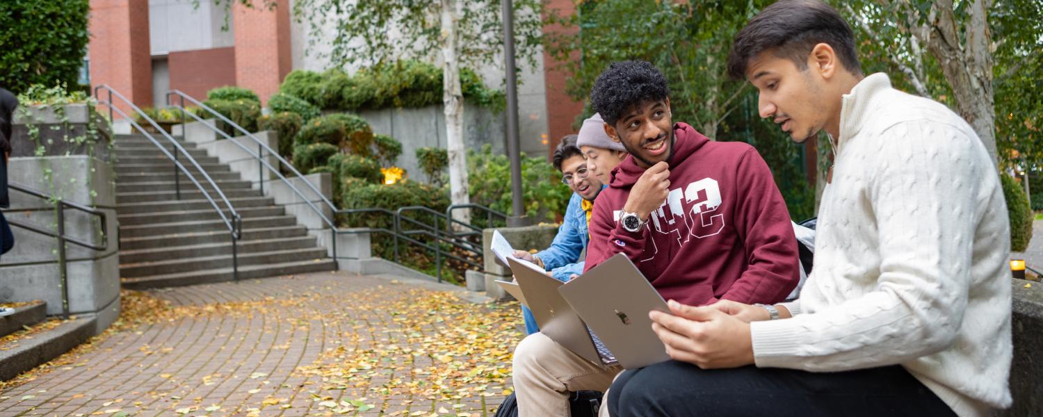 Four students interact near Martin Square on the SPU campus in the autumn.